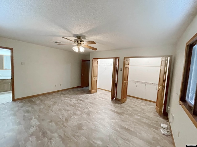 unfurnished bedroom featuring baseboards, a textured ceiling, multiple closets, and a ceiling fan