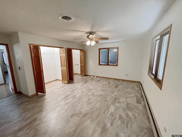 unfurnished bedroom featuring a textured ceiling, baseboards, visible vents, and baseboard heating