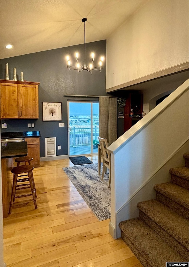 999 Eagle Dr, Douglas, WY 82633 - kitchen featuring brown cabinets, high vaulted ceiling, light wood-type flooring, a chandelier, and dark countertops