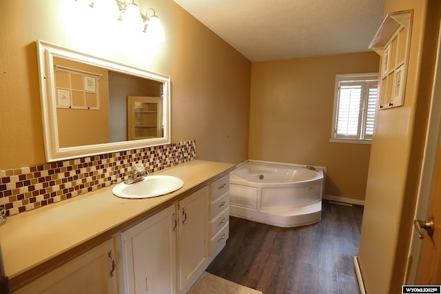 bathroom featuring vanity, a garden tub, wood finished floors, baseboards, and backsplash