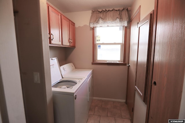 laundry area featuring baseboards, cabinet space, light tile patterned floors, and washing machine and dryer
