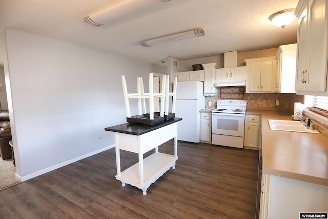 kitchen with decorative backsplash, a sink, under cabinet range hood, white appliances, and dark wood-type flooring
