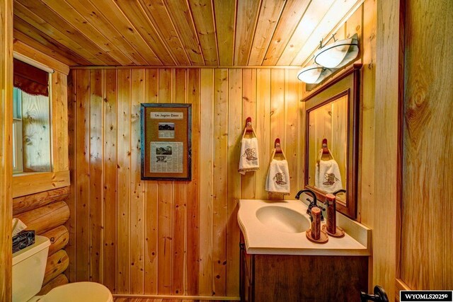 18 High Meadows Rd, Buffalo, WY 82834 - half bathroom with wooden ceiling, wood walls, vanity, and toilet