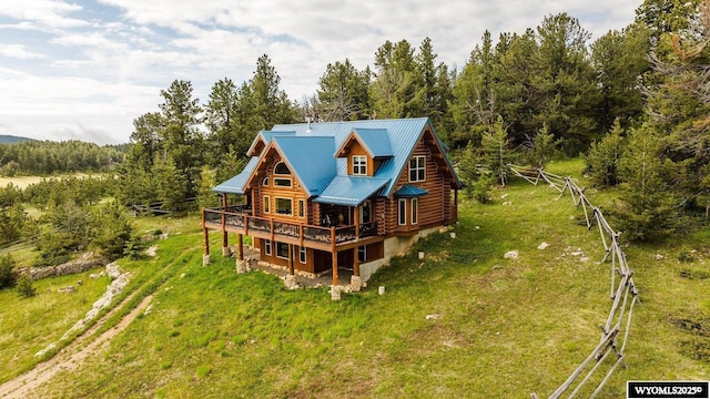 18 High Meadows Rd, Buffalo, WY 82834 - rear view of house with a wooden deck, log siding, metal roof, a view of trees, and a yard