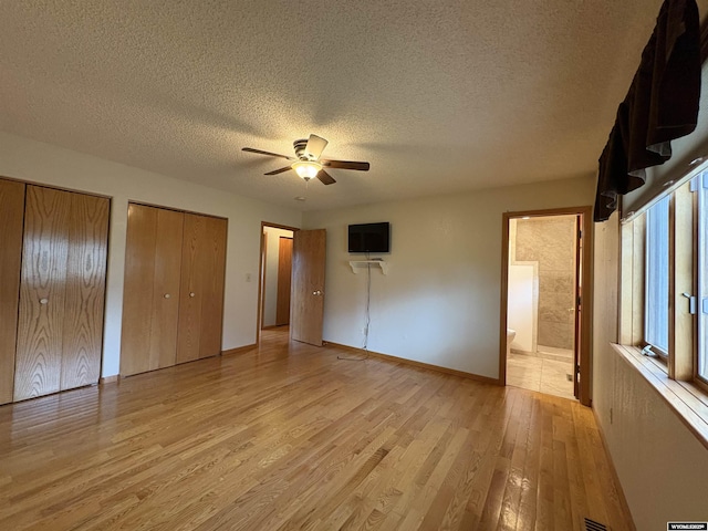 2327 Crestview Dr, Torrington, WY 82240 - unfurnished bedroom with light wood-style floors, baseboards, two closets, and a textured ceiling