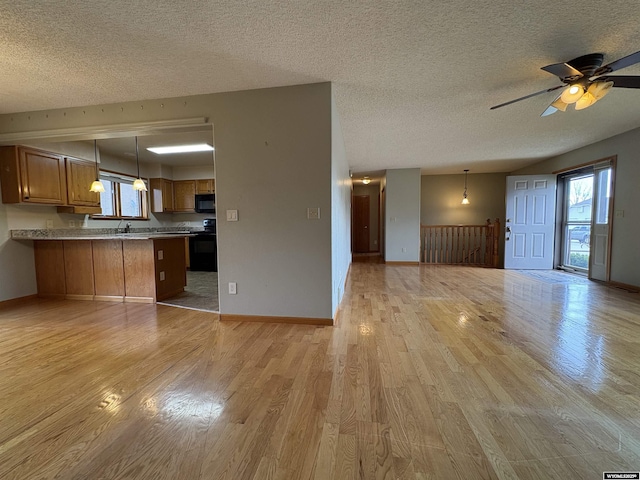 2327 Crestview Dr, Torrington, WY 82240 - unfurnished living room with baseboards, ceiling fan, light wood-style flooring, and a textured ceiling