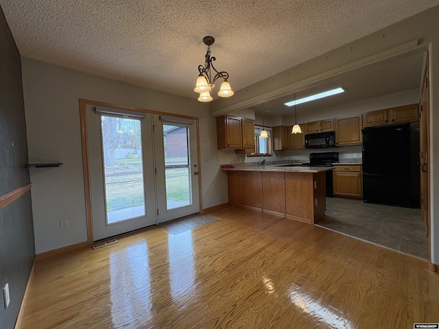2327 Crestview Dr, Torrington, WY 82240 - kitchen featuring a peninsula, black appliances, light wood-type flooring, and a textured ceiling