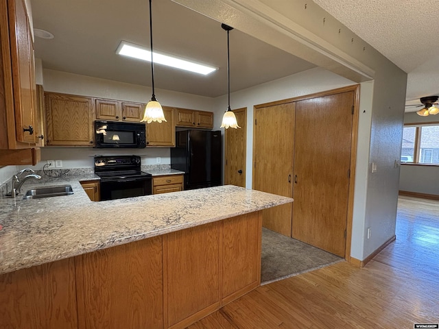 2327 Crestview Dr, Torrington, WY 82240 - kitchen featuring brown cabinetry, light wood-type flooring, a sink, black appliances, and a peninsula