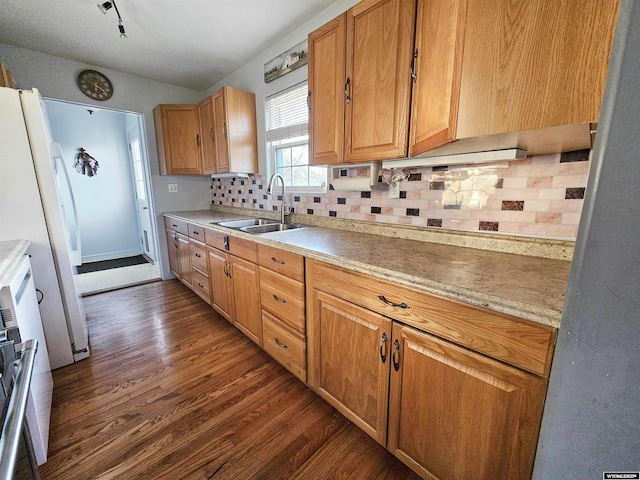 kitchen featuring freestanding refrigerator, dark wood-type flooring, light countertops, tasteful backsplash, and a sink