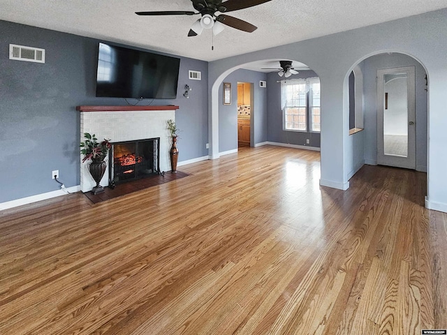 unfurnished living room featuring a ceiling fan, a textured ceiling, visible vents, and a fireplace