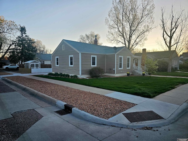 property exterior at dusk featuring a lawn and a chimney