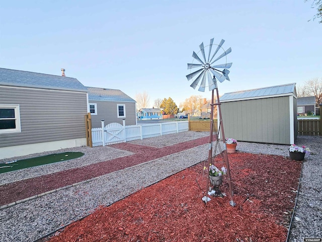 view of yard with a fenced backyard, a gate, an outbuilding, and a shed