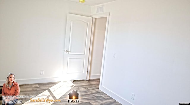 spare room featuring visible vents, baseboards, and wood finished floors