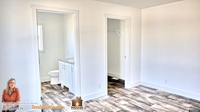 unfurnished bedroom featuring baseboards, ensuite bathroom, a closet, and light wood finished floors