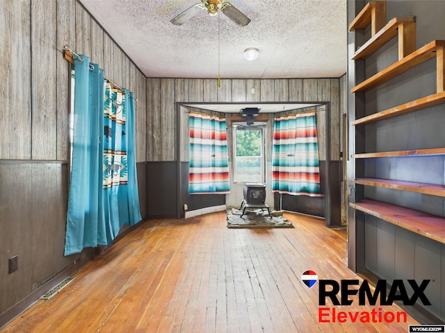 602 S 6th St, Basin, WY 82410 - interior space with a ceiling fan, a textured ceiling, visible vents, a wood stove, and hardwood / wood-style flooring