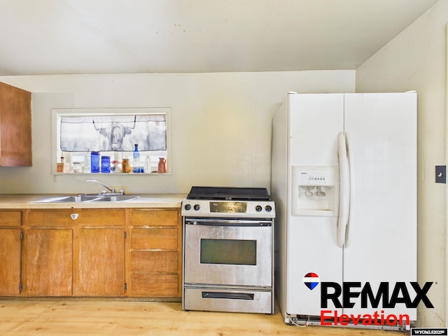 602 S 6th St, Basin, WY 82410 - kitchen with light wood-style floors, light countertops, a sink, gas stove, and white fridge with ice dispenser