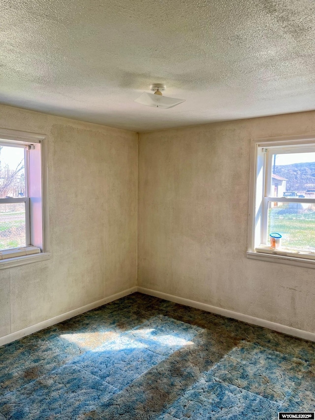 carpeted spare room with baseboards, a textured ceiling, and ceiling fan