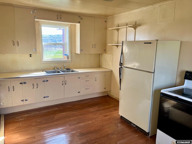 kitchen featuring a sink, electric range oven, light countertops, freestanding refrigerator, and wood finished floors