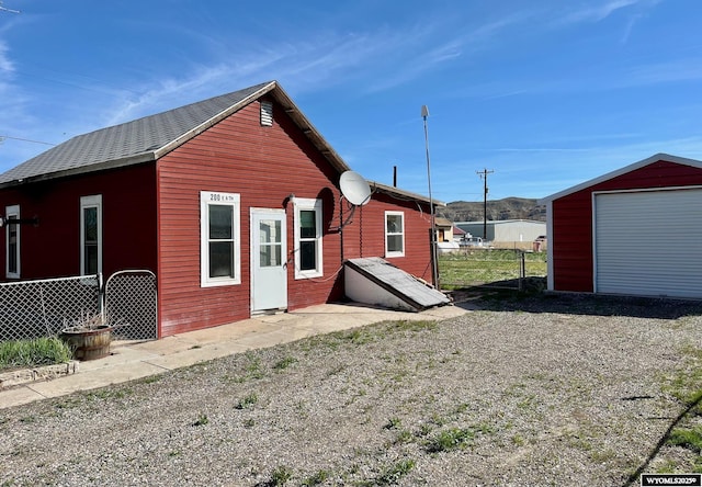 back of house with fence and an outbuilding