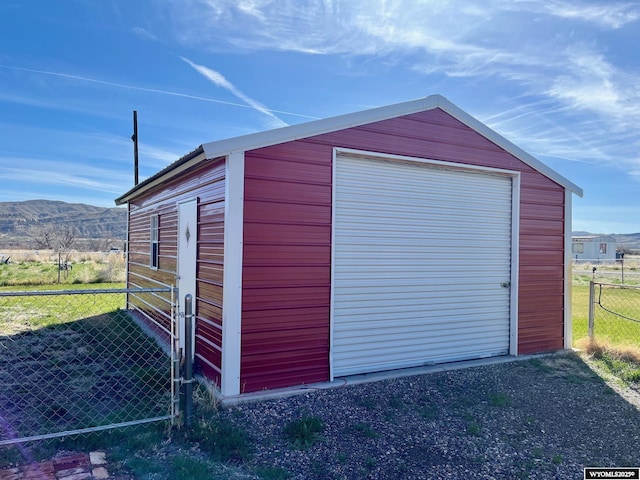 view of outdoor structure with an outdoor structure, a mountain view, and fence