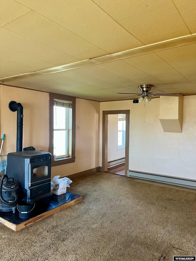 living area featuring a wood stove, a baseboard heating unit, and a wealth of natural light
