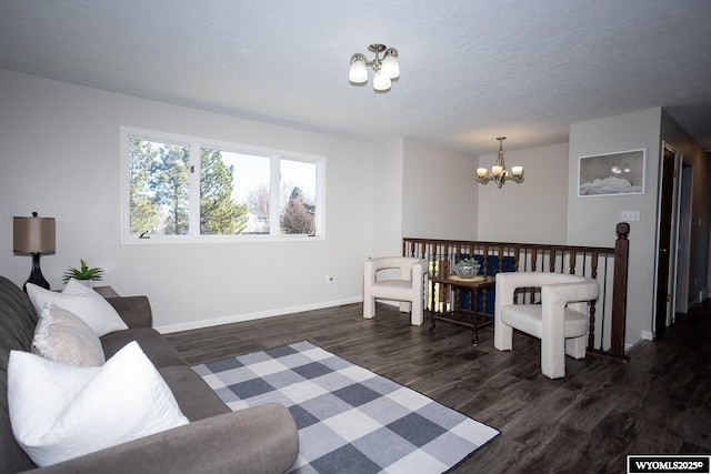 living area with a textured ceiling, baseboards, an inviting chandelier, and dark wood-type flooring