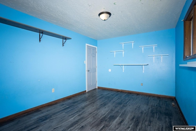 spare room featuring dark wood-type flooring, a textured ceiling, and baseboards