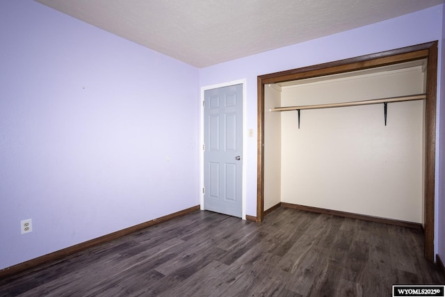 unfurnished bedroom with baseboards, dark wood finished floors, and a closet