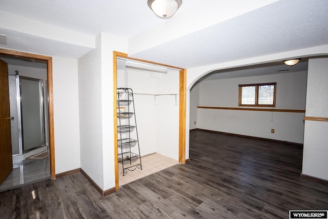 interior space featuring baseboards, arched walkways, and wood finished floors