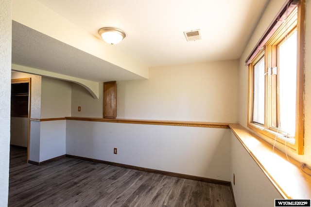 spare room featuring visible vents, baseboards, and dark wood-type flooring