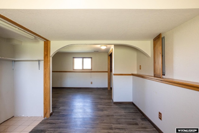 hallway featuring arched walkways and wood finished floors