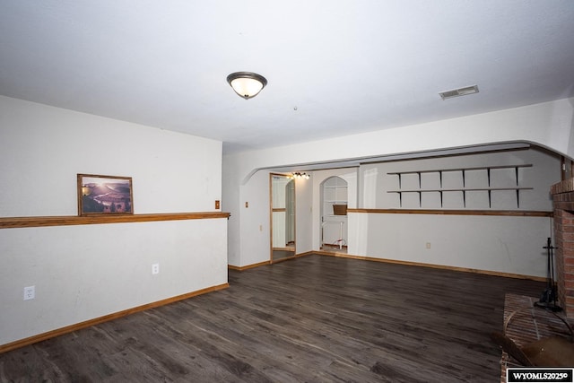 unfurnished room featuring arched walkways, baseboards, visible vents, and wood finished floors