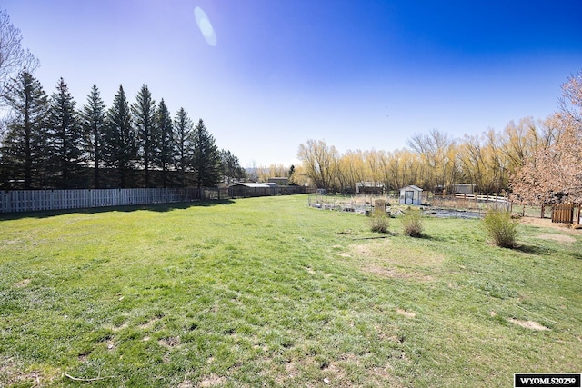 view of yard featuring an outdoor structure, a fenced backyard, and a storage shed