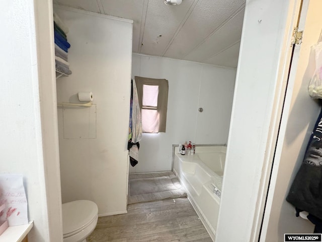 full bathroom featuring a bath, toilet, and wood finished floors