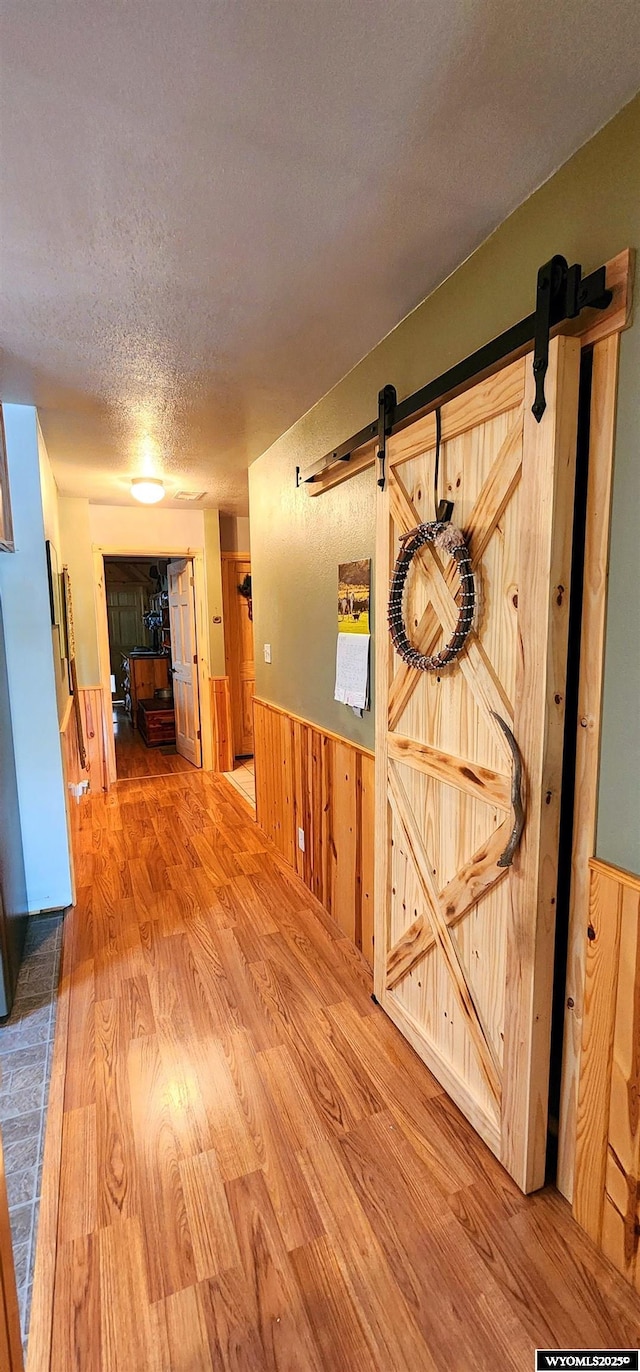 5421 S Okeepa, Casper, WY 82604 - corridor featuring a barn door, a textured ceiling, wood finished floors, and a wainscoted wall