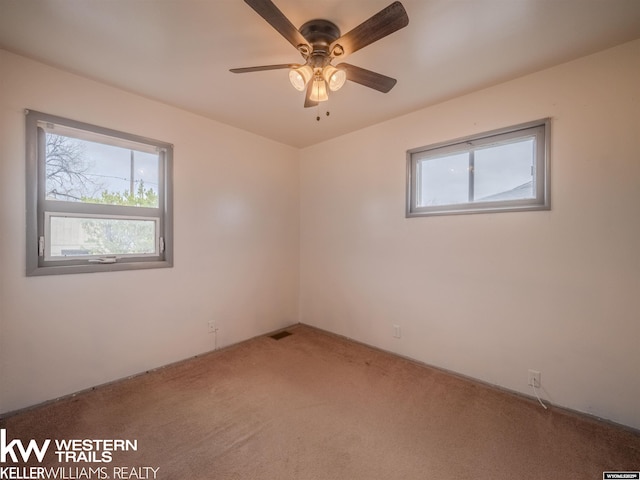 spare room featuring light colored carpet, a ceiling fan, and visible vents