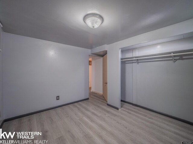 unfurnished bedroom with baseboards, a closet, and light wood-type flooring