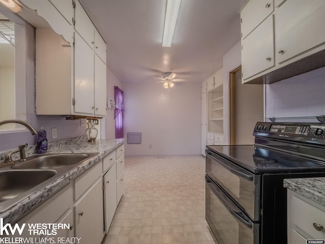 kitchen with light floors, ceiling fan, white cabinets, range with two ovens, and a sink