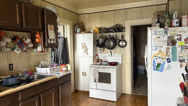 kitchen featuring light countertops, dark brown cabinetry, white appliances, and a sink