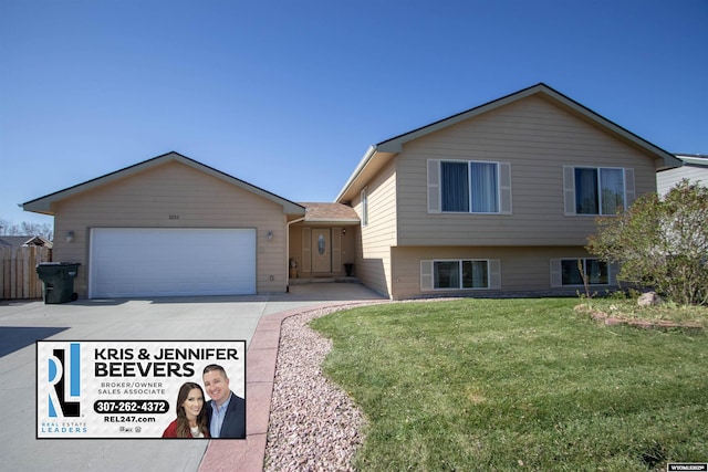 tri-level home featuring concrete driveway, a front lawn, and a garage