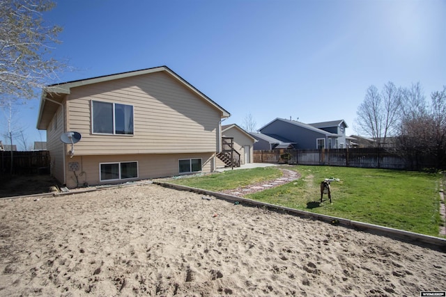 rear view of house with a fenced backyard and a yard