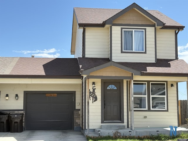 view of front of home featuring roof with shingles, concrete driveway, an attached garage, and fence