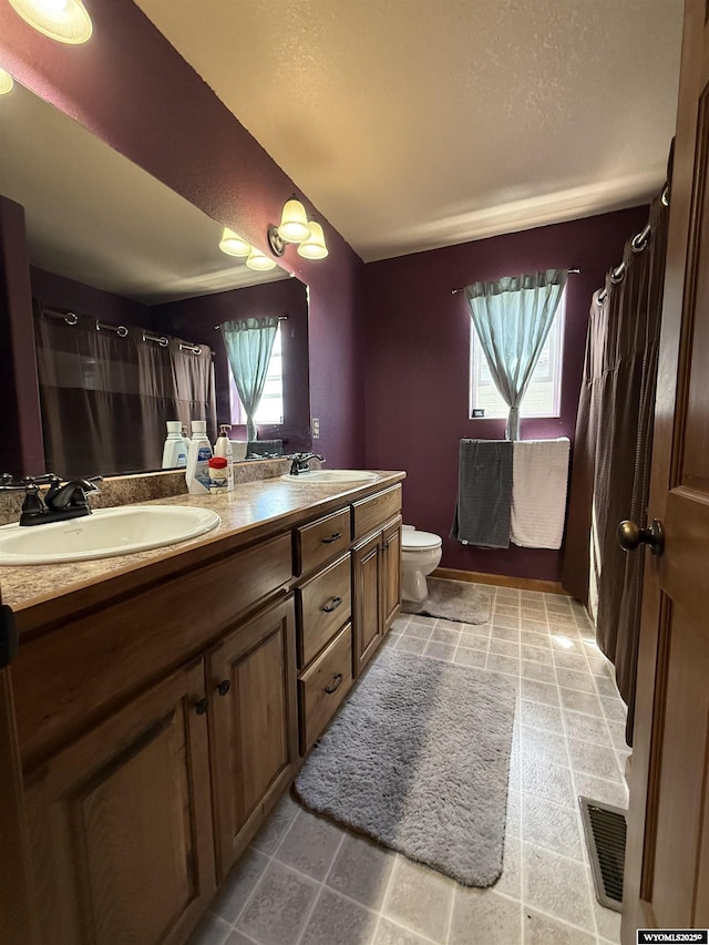 full bath with visible vents, a healthy amount of sunlight, and a sink