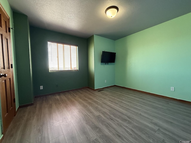 unfurnished bedroom with a textured ceiling, baseboards, and wood finished floors
