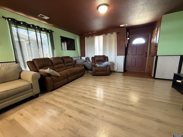 living area featuring a wealth of natural light, light wood-type flooring, and visible vents