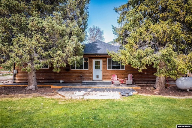 back of property with a yard, a shingled roof, and faux log siding