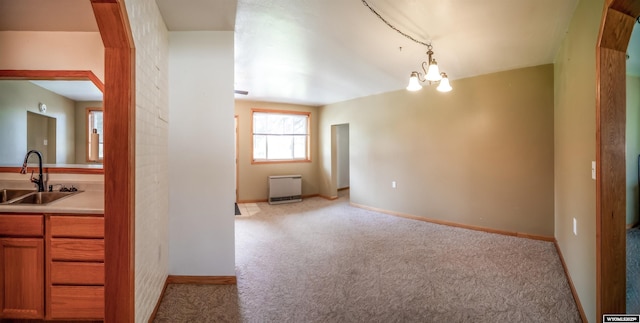 carpeted spare room featuring a sink, a chandelier, baseboards, and arched walkways