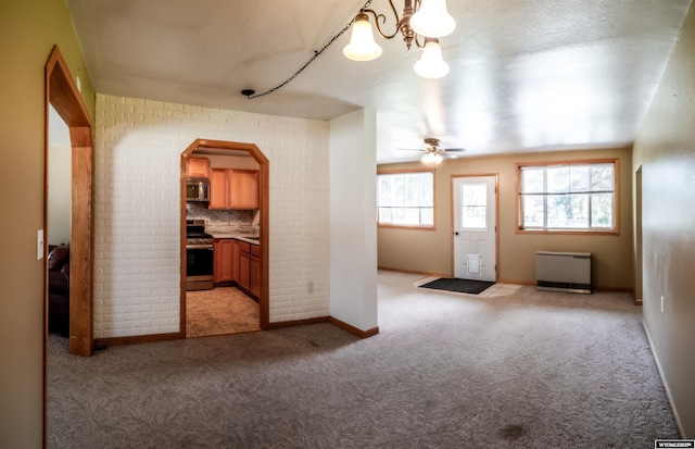 foyer with light carpet, ceiling fan, arched walkways, and baseboards