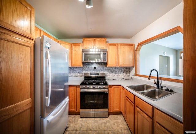 kitchen featuring appliances with stainless steel finishes, a sink, tasteful backsplash, and light countertops