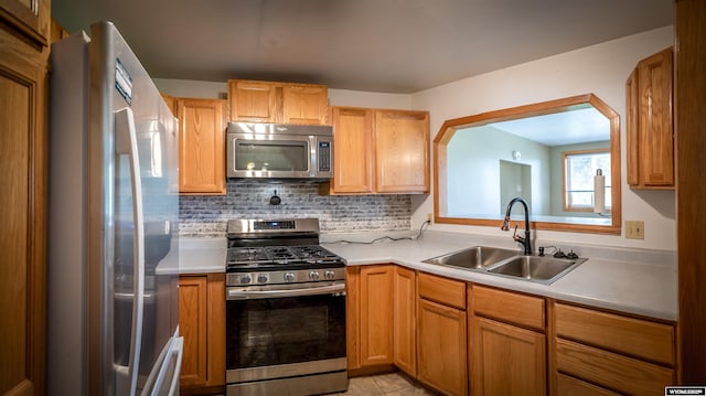 kitchen featuring appliances with stainless steel finishes, a sink, light countertops, tasteful backsplash, and light tile patterned flooring
